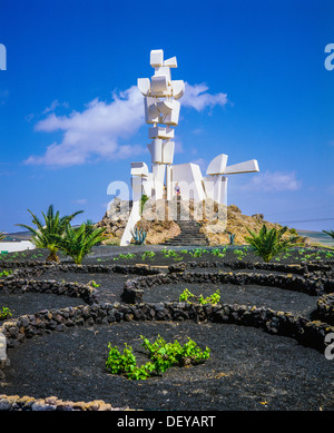 Grape vines growing in volcanic soil and Monument to Fertility by César Manrique, La Geria Mozaga Lanzarote Canary Islands Spain Europe Stock Photo