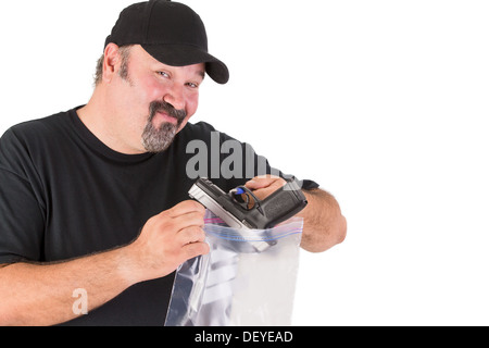 Crime scene investigator founds a gun, he has a sure look on his face while he is placing gun in to a evidence bag Stock Photo