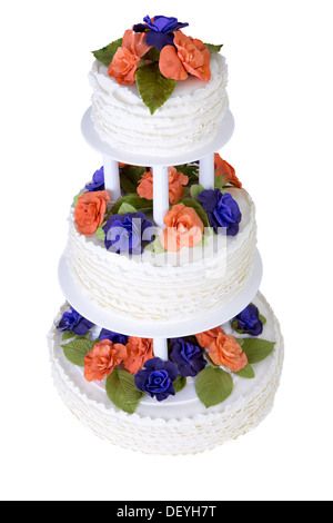 Isolated three tier ruffled white wedding cake decorated with orange and purple roses and green leafs Stock Photo