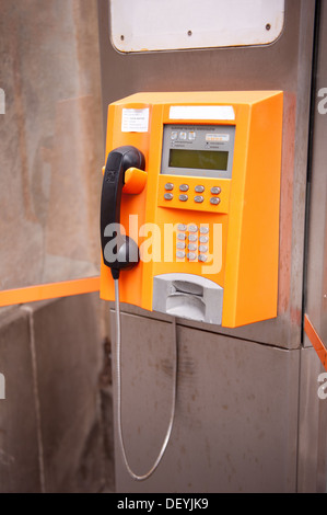 Old yellow telephone kiosk and black handset Stock Photo