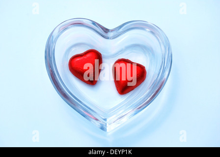 Two heart-shaped chocolates in a glass bowl, symbolic image for togetherness Stock Photo