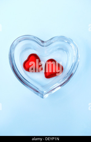 Two heart-shaped chocolates in a glass bowl, symbolic image for togetherness Stock Photo