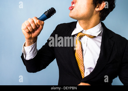 Young businessman with microphone is singing karaoke Stock Photo