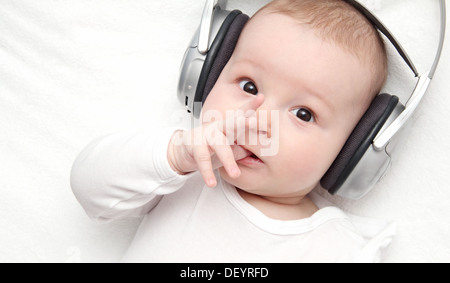 baby boy with headphone lies on back Stock Photo