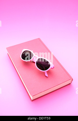 Pink sunglasses lying on a book Stock Photo