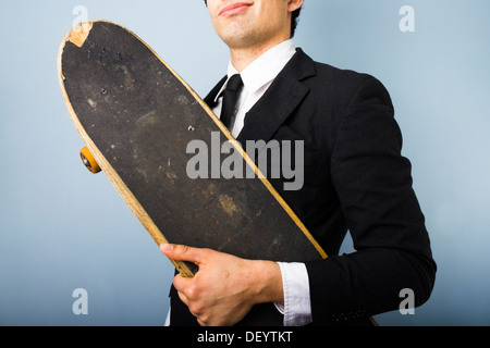 Young businessman looking smug and happy with his skateboard Stock Photo