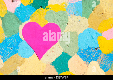 Heart-shaped slip of paper on a colorfully spotted wall Stock Photo