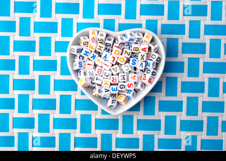 Beads, letter cubes in a heart-shaped bowl Stock Photo