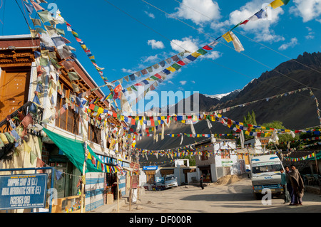 India, Jammu & Kashmir, Ladakh, the main street in Alchi with building and prayer flags and four Ladakh men Stock Photo