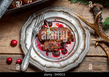 Healthy venison with cranberries and rosemary served on an old metal plate Stock Photo