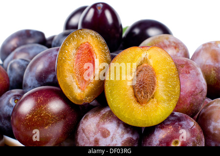 Fresh red plums with one sliced open to reveal the succulent yellow flesh and pip, over white Stock Photo