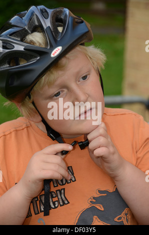 A young boy puts on a crash helmet before cycling Stock Photo