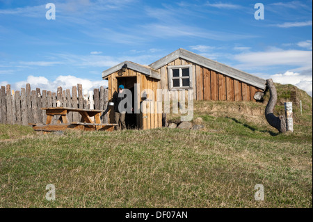 Woman walking through a door carrying a pot, wooden cabin, campground, Moeðrudalur farm, Iceland's highest situated farm Stock Photo