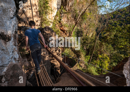 Woman walking on a bamboo bridge, hike through the jungle, Soppong or Pang Mapha area, Mae Hong Son province, Northern Thailand Stock Photo