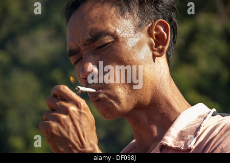 Man from the Shan or Thai Yai ethnic minority is lighting a cigarette, Soppong or Pang Mapha area, Northern Thailand, Thailand Stock Photo