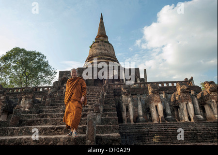 Buddhist monk on the stairs, laterite chedi with destroyed elephant statues, stepped temple of Wat Chang Lom Stock Photo