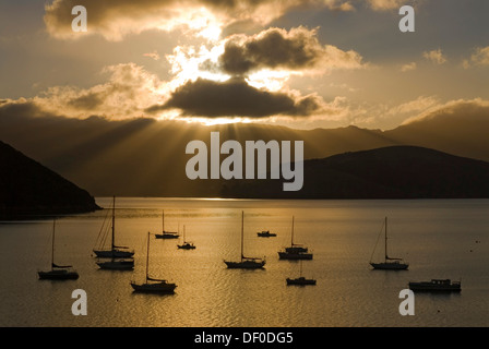 Sun beams over Akaroa Harbour and backlit boats in early morning light, Banks Peninsula, Canterbury region, South Island Stock Photo
