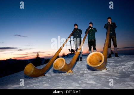 Alpine horn players, traditional costume, winter, snow, mountains, Chiemgau, Bavaria Stock Photo