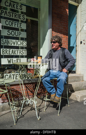 A man dressed in blue jeans, leather vest and sunglasses eats breakfast outside at a sidewalk cafe in Waldoboro, Maine. Stock Photo