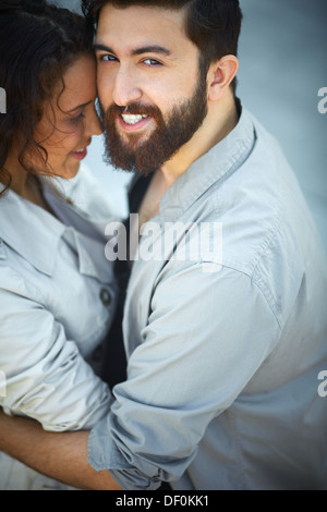 Image of happy man looking at camera while embracing his sweetheart Stock Photo