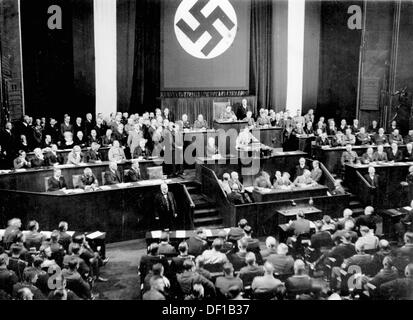 The image from the Nazi Propaganda! shows Reich Chancellor Adolf Hitler delivering a speech to the Reichstag in the Kroll Opera House in Berlin, Germany, 17 May 1933. To the left, first row (r-l): Vice Chancellor Franz von Papen, Foreign Minister Konstantin von Neurath, Reich Minister of the Interior Wilhelm Frick; second row (r-l): Minister of Economics and Agriculture Alfred Hugenberg, Minister for Labour Franz Seldte, Minister of War Werner von Blomberg. Behind Hitler, Hermann Göring. Fotoarchiv für Zeitgeschichte Stock Photo