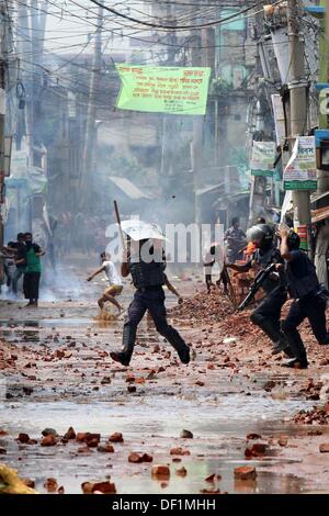 Narayanganj, Bangladesh. 26th Sep, 2013. Bangladeshi police officials take cover as striking garment workers throw stones during a protest in Narayanganj on September 26, 2013. Most Bangladesh garment factories have reopened after five days of violent protests over wage hikes for textile workers, after the government vowed to crack down on the unrest 'with all force . Stock Photo
