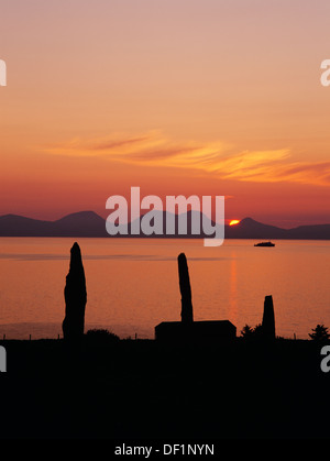 Ballochroy standing stones, Kintyre, Argyll, looking NNW to the Paps of Jura at midsummer solstice sunset with CalMac Islay car ferry. Stock Photo