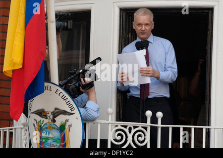 Julian Assange addresses the media and supporters while British policemen stand outside the Ecuadorian Embassy in London, Britai Stock Photo