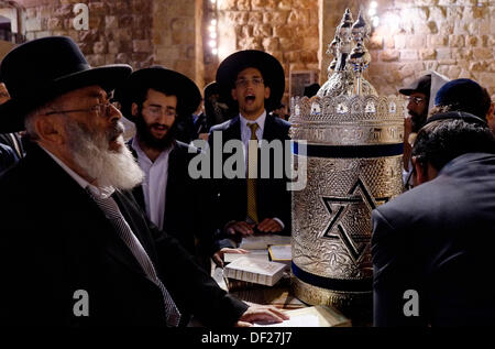 Religious Jews celebrate the Simchat Torah in the Western Wall in Jerusalem on 26 September 2013. Simchat Torah is a Rabbinical festival celebrating the completion and new beginning of the year's the first five books of the old testament reading cycle. Simchat Torah is celebrated by taking all the Torah scrolls out of the ark in synagogue and spending the evening dancing, singing, and rejoicing. Stock Photo