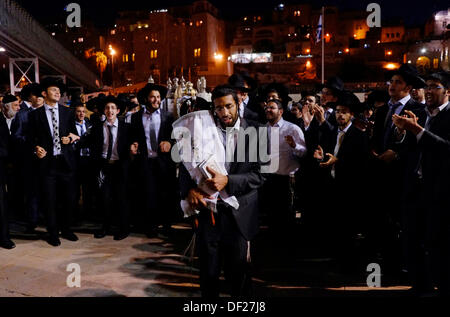 Ultra Orthodox Religious Jewish men dancing with scrolls of Torah as they celebrate the Simchat Torah a Jewish holiday that celebrates and marks the conclusion of the annual cycle of public Torah readings, and the beginning of a new cycle in the Western Wall old city East Jerusalem Israel Stock Photo