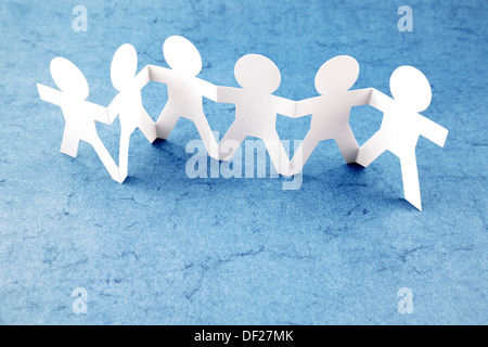 Group of paper chain people holding hands together. Teamwork concept Stock Photo