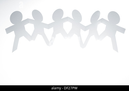 Team of six paper doll people holding hands. Teamwork concept Stock Photo