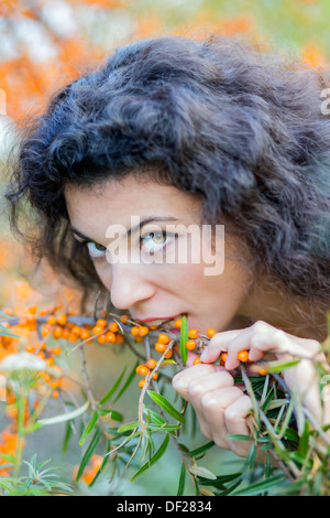 Nice looking young woman eat gooseberries from branch Stock Photo