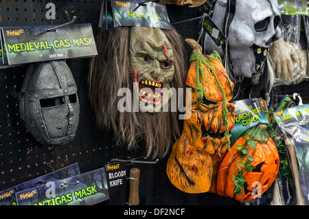 Spooky, scary Halloween holiday masks of monsters, demons and ghouls hanging on store display. Stock Photo