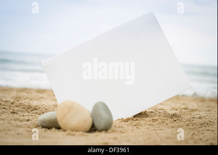 Blank white sign on a sand beach with stones and pebbles Stock Photo