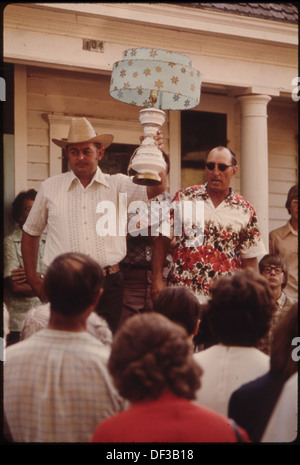 AN AUCTIONEER'S HELPER HOLDS A LAMP UP AS THE AUCTIONEER ASKS FOR BIDDING ON IT AT AN AUCTION IN NEW ULM, MINNESOTA.... 558290 Stock Photo