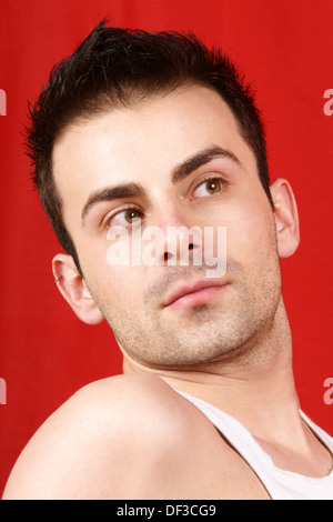 Portrait of a young man with brown eyes and brown hair over a red background. Stock Photo