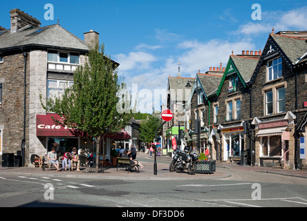 People tourists visitors outside shops stores businesses in the town centre in summer Windermere Cumbria England UK United Kingdom GB Great Britain Stock Photo