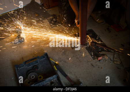 A construction worker using an angle grinder to cut a metal pipe. Stock Photo