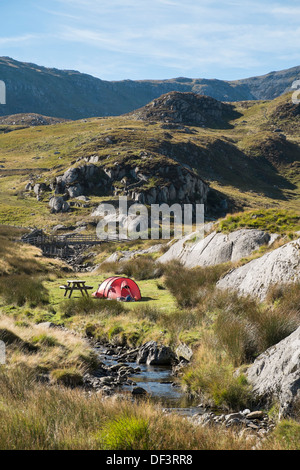 Tent camped by a stream on Willie's Farm campsite in mountains of Snowdonia National Park Ogwen Valley North Wales UK Britain Stock Photo