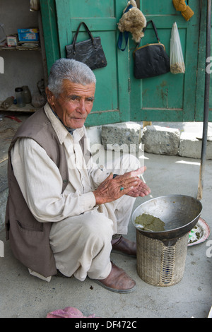 Shopkeeper rolling niswar (a type of chewing tobacco) on the verandah of his shop, Karimabad, Hunza Valley, Gilgit-Baltistan, Pakistan Stock Photo