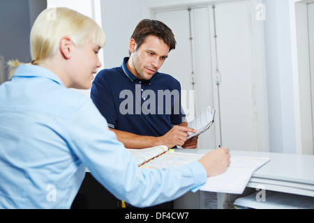 Man with appointment book scheduling an appointment at reception of dentist Stock Photo