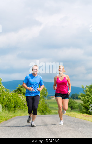 Couple, man and woman doing jogging or outdoor sport for fitness on rural street Stock Photo