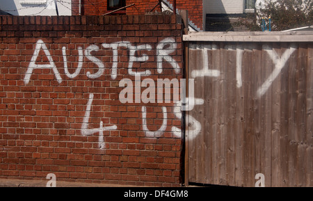 Graffiti condemning economic policy 'Austerity 4 Us' White paint on brick wall Cardiff Wales UK Stock Photo