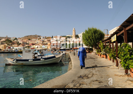 Greek Orthodox Priest walking along Halki Chalki harbour Greek Islands The Dodecanese Greece Stock Photo