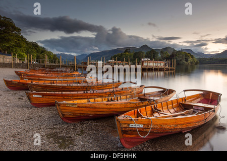 Rowing boats on the shore of Derwent Water in the Lake District as the sun sets with Catbells in the background. Stock Photo