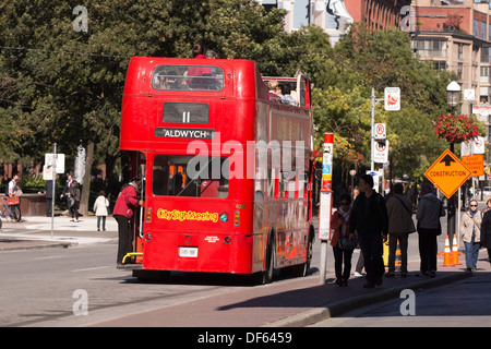People boarding a red double decker tour bus on Front St. in downtown Toronto Stock Photo