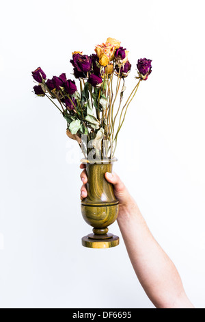 Hand holding a wooden vase of dead flowers on white background Stock Photo