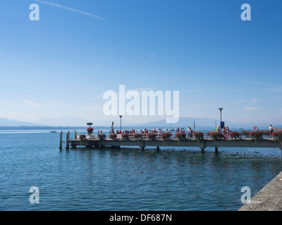 Nyon, a Swiss town on the shores of Lake Geneva in Switzerland, sunny panorama of lake and pier with people waiting for the boat Stock Photo