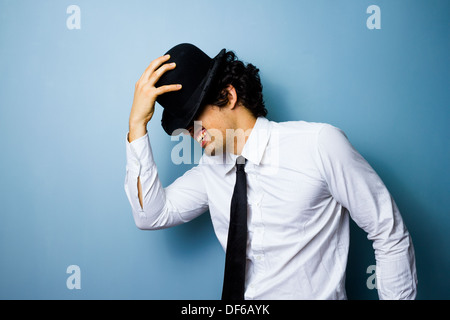 Smiling young man is tipping his bowler hat Stock Photo